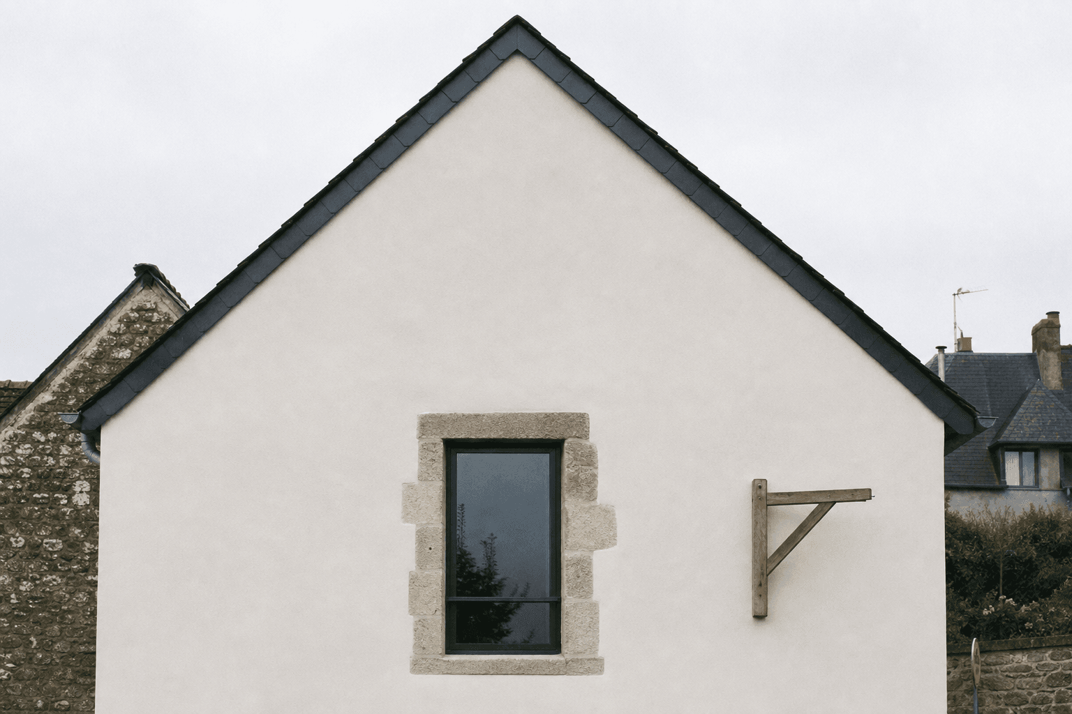 Le pignon d'une maison de village, mur blanc et toit d'ardoise neuf